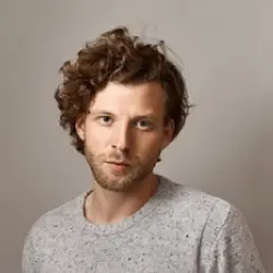 homme châtain décoiffé avec un pull en laine gris