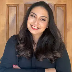 jeune femme aux longs cheveux noirs souriant les bras croisés